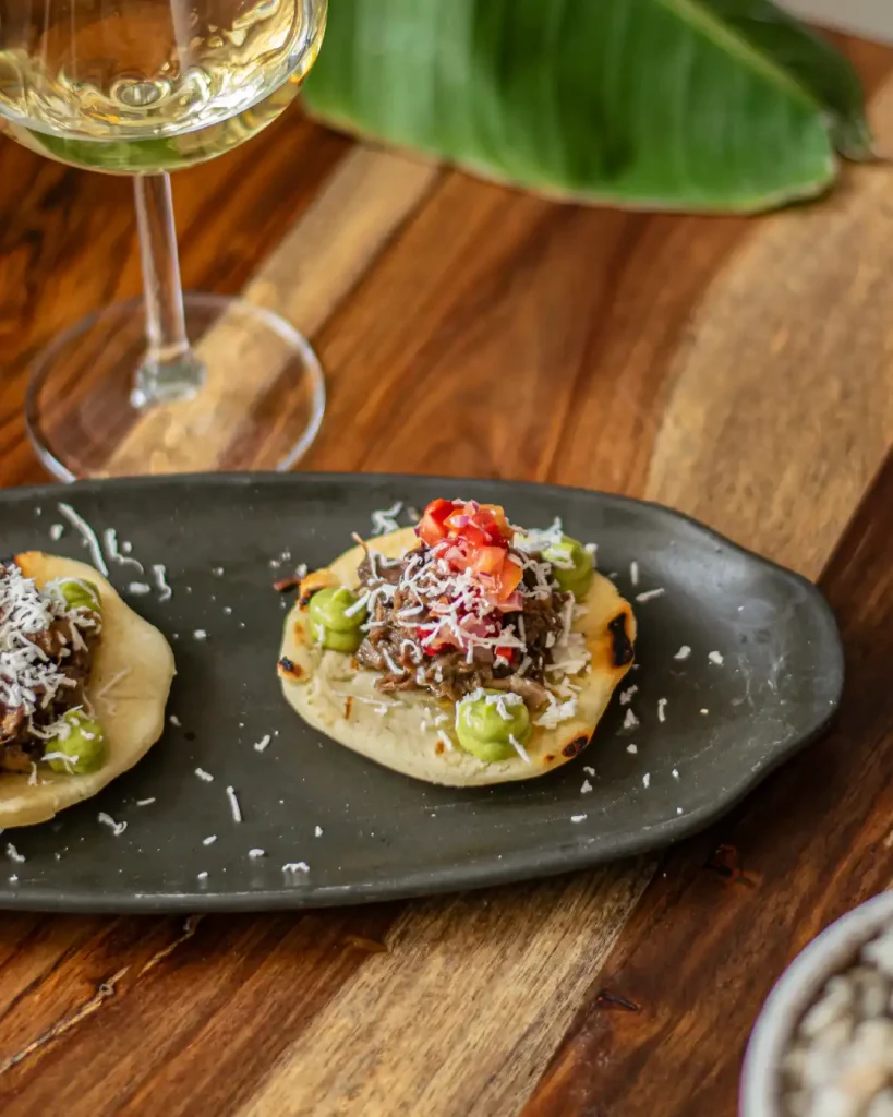 Arepa de maíz, rabo de toro desmigado, pico de gallo, guacamole y queso costeño