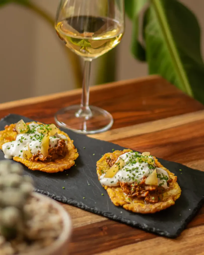 Carrillada de cerdos con naranja, desmigada, sobre patacón crujiente y tzatziki